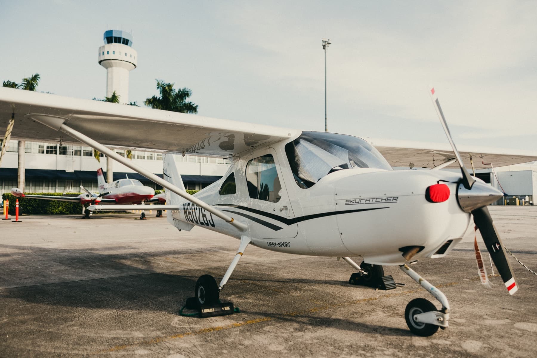 Cessna 162 Skycatcher with the control tower behind